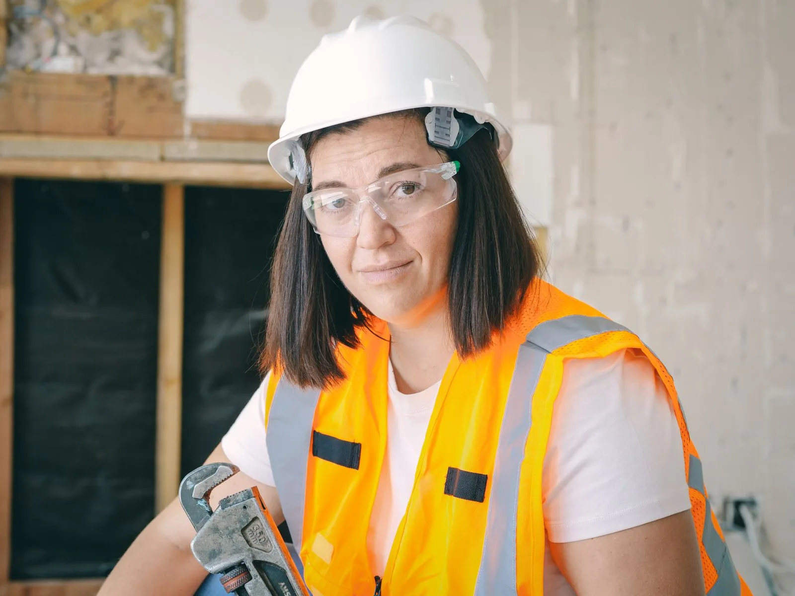 Plumbing professional in a hard hat and safety vest holding a pipe wrench for emergency plumbing service in Miami