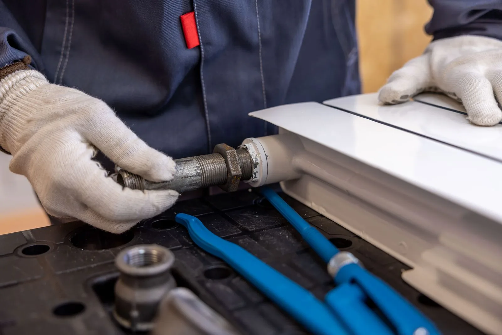 Plumber's hands fitting a threaded pipe connection during gas line repair service in a Miami home