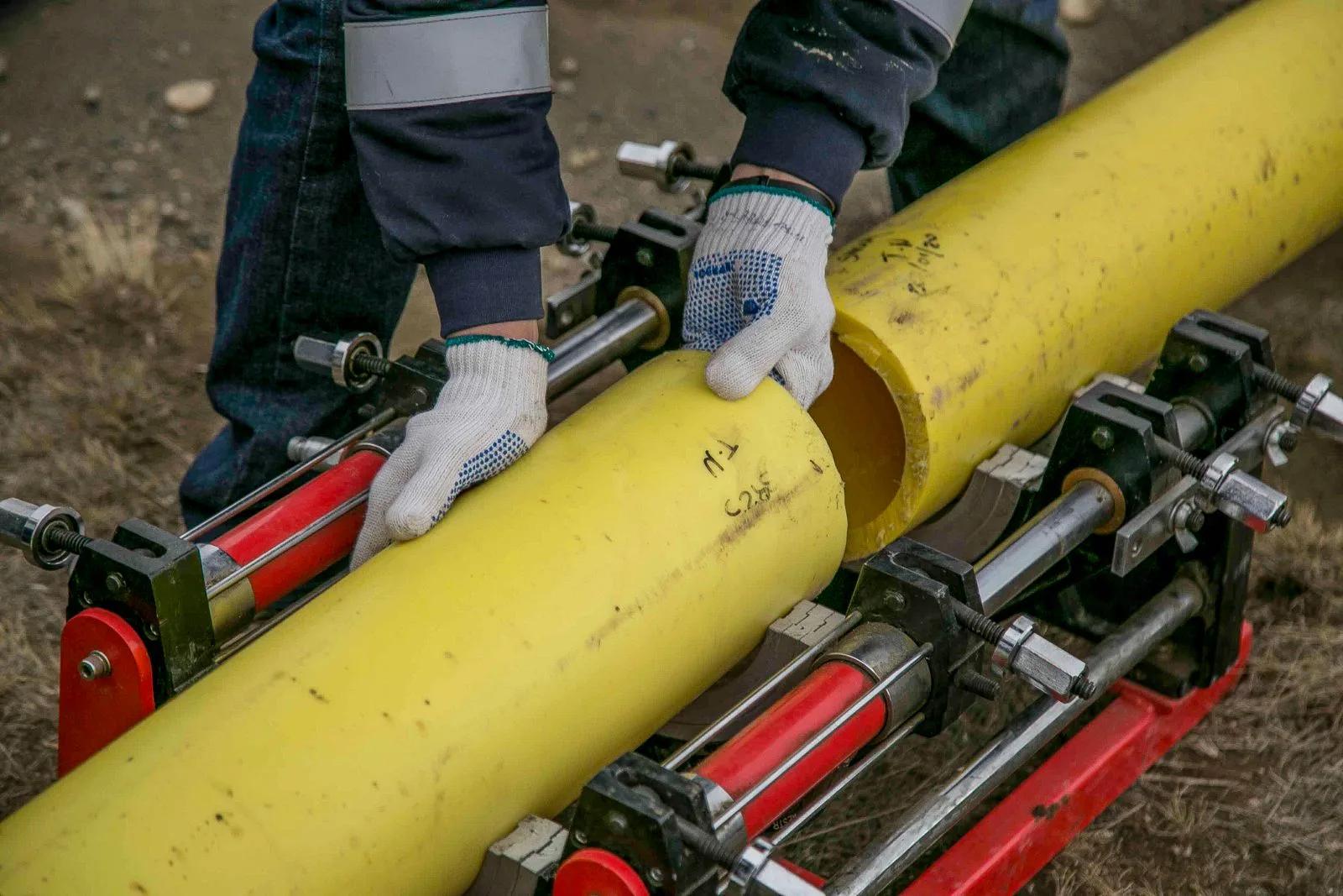 Worker joining yellow gas supply pipes with fusion equipment during gas line installation service in Miami