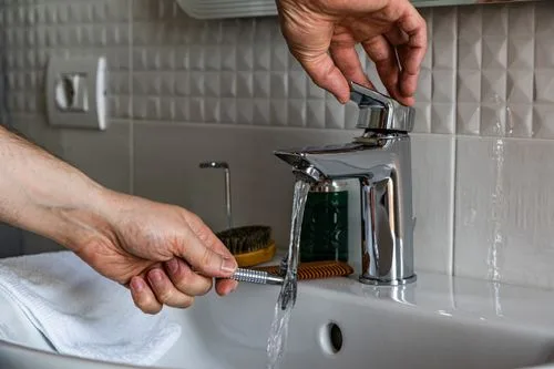Hands inspecting a bathroom faucet with a tool checking for drips during leak detection in a Miami home
