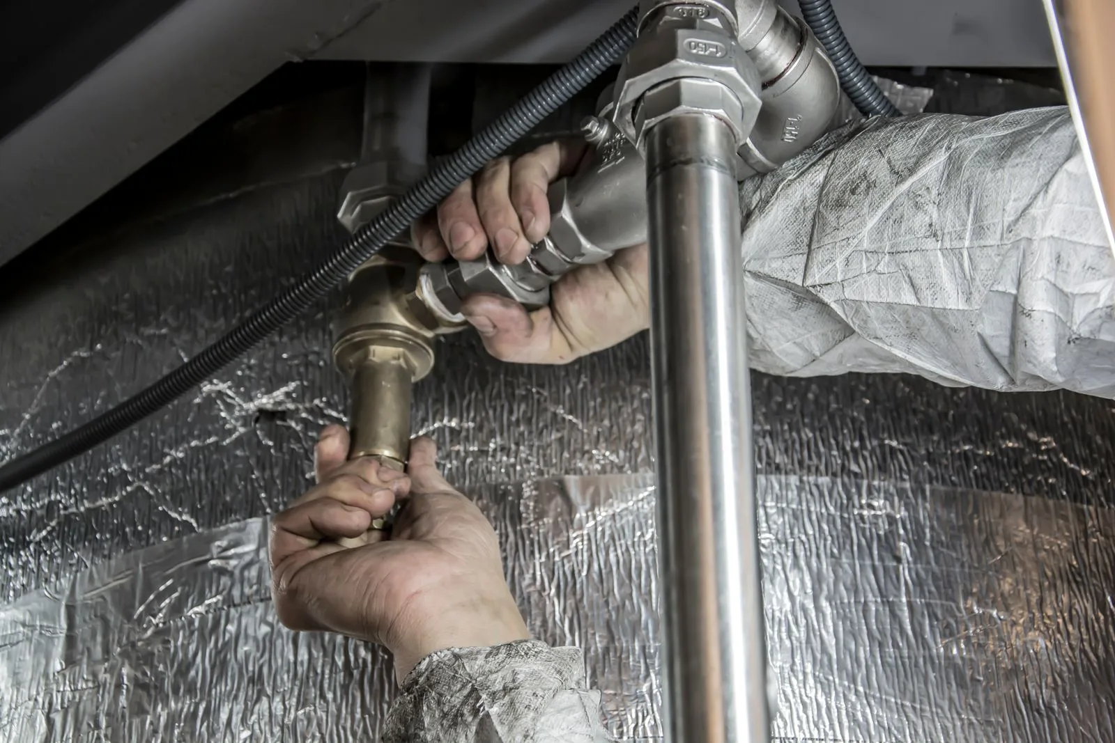 Plumber's hands installing steel pipe fittings during a pipe repair job in a Miami home