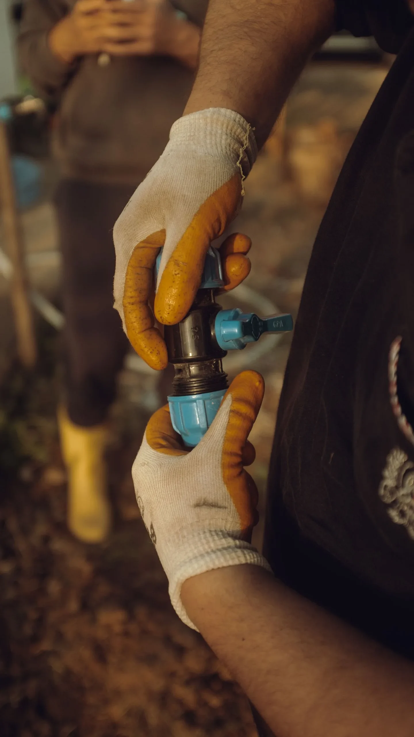 Worker with gloved hands assembling a water pipe outdoors in Miami