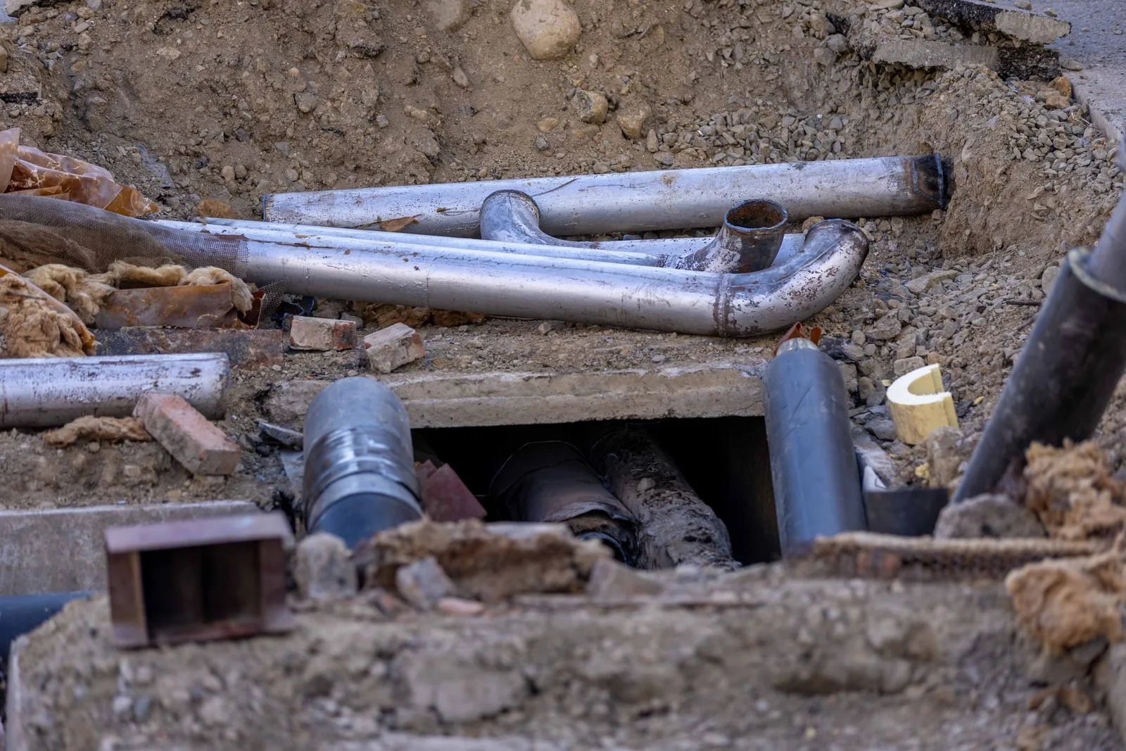 Exposed pipes in an excavated trench during a sewer line repair in Miami