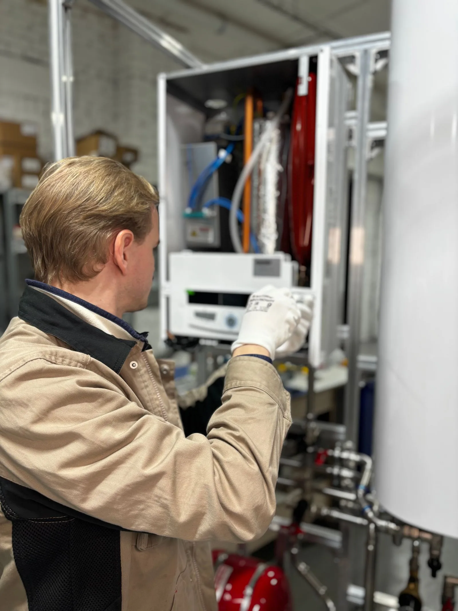 Technician's gloved hands adjusting the control panel of a water heater during a repair visit in Miami