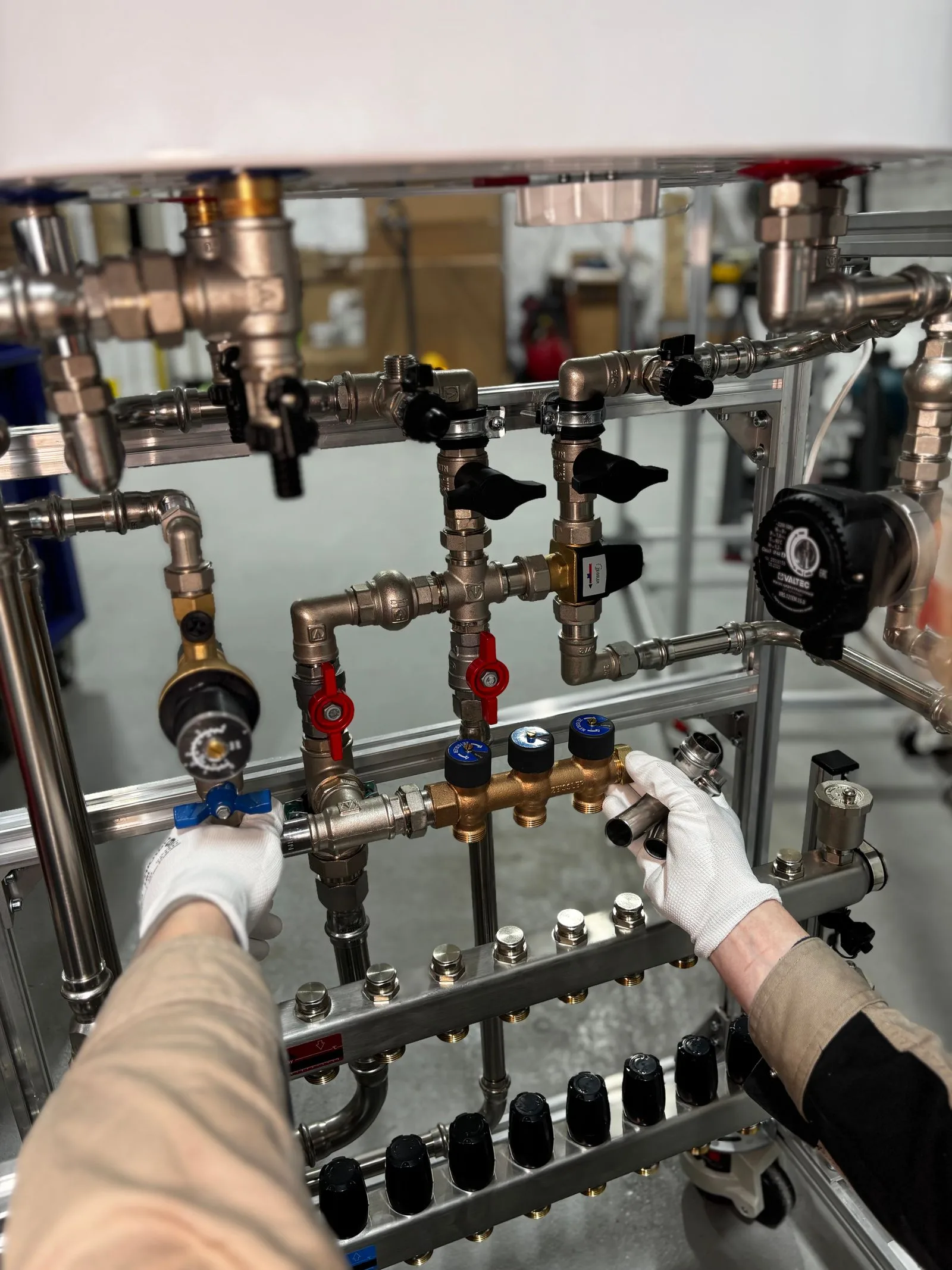 Close-up of a technician's gloved hands working on water heater valves and pipe connections in Miami